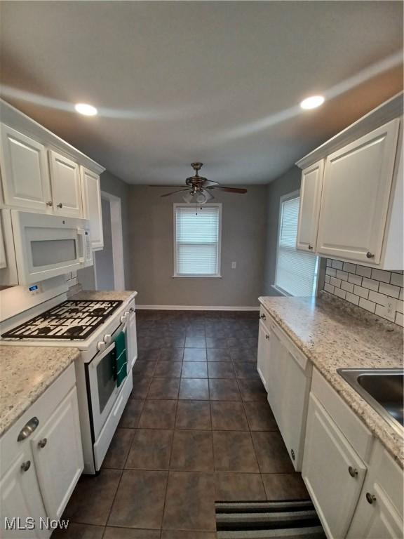 kitchen featuring white cabinetry, white appliances, dark tile patterned floors, and backsplash