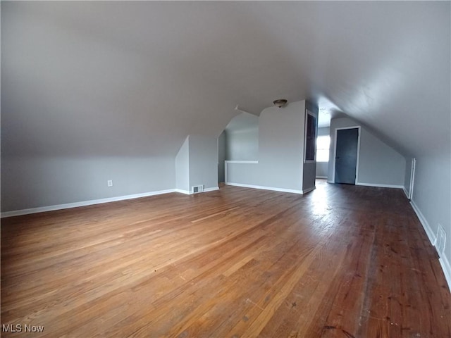 additional living space with hardwood / wood-style flooring and vaulted ceiling