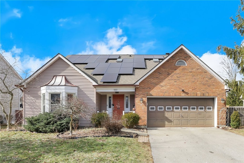 view of front of home featuring a garage, a front yard, and solar panels