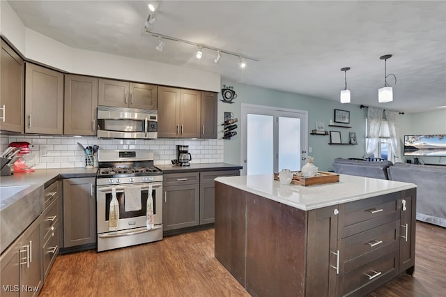 kitchen featuring stainless steel appliances, decorative backsplash, a kitchen island, dark hardwood / wood-style flooring, and decorative light fixtures