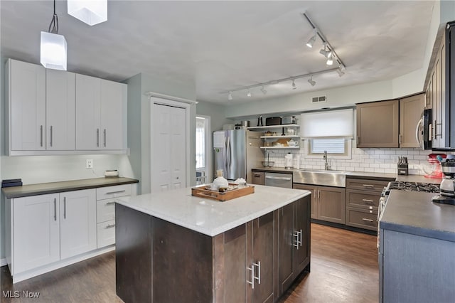 kitchen with stainless steel appliances, a kitchen island, sink, and decorative light fixtures