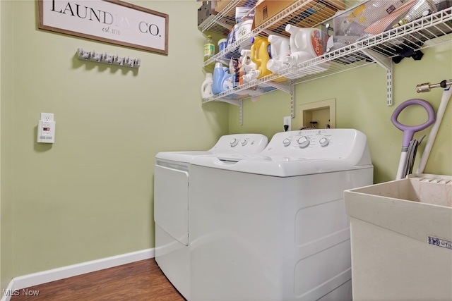 laundry area with hardwood / wood-style flooring, washing machine and dryer, and sink