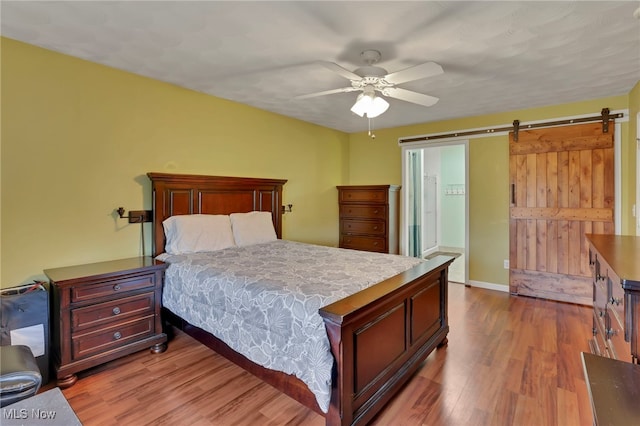 bedroom with wood-type flooring, a barn door, and ceiling fan