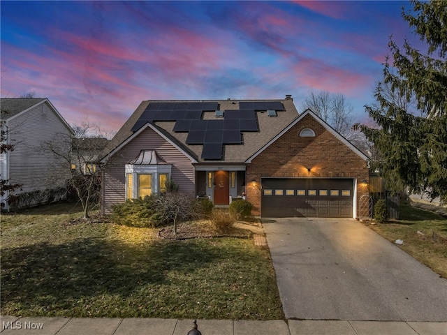 view of property with a garage, a lawn, and solar panels