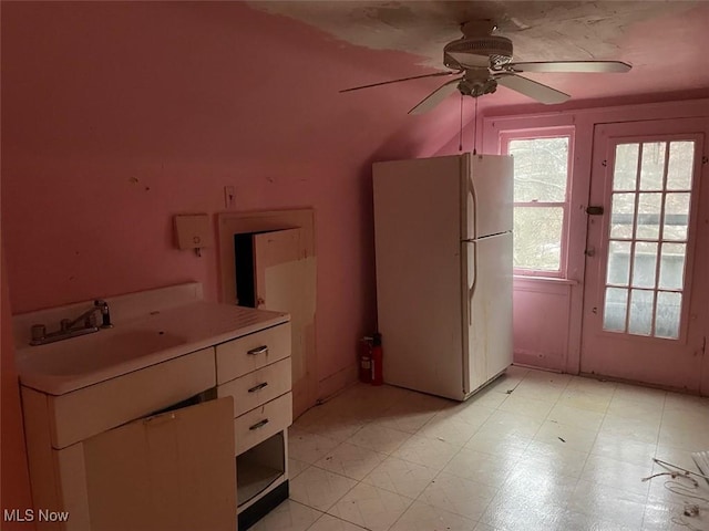 kitchen featuring ceiling fan, sink, white fridge, and white cabinets