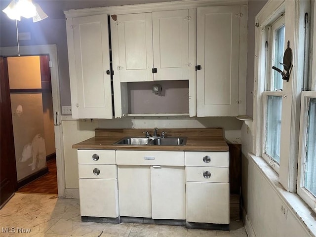 kitchen featuring white cabinetry, butcher block counters, and sink