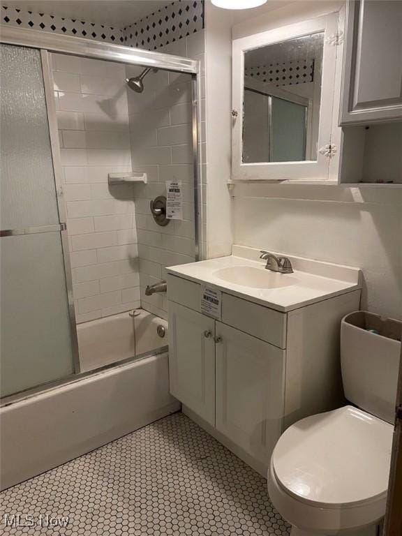 full bathroom featuring toilet, vanity, and bath / shower combo with glass door