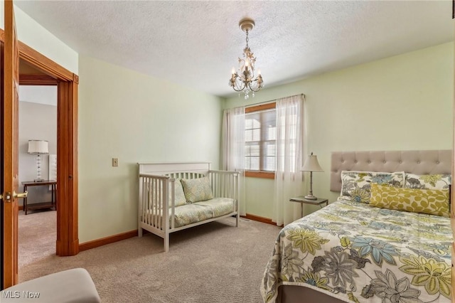 carpeted bedroom featuring a chandelier and a textured ceiling