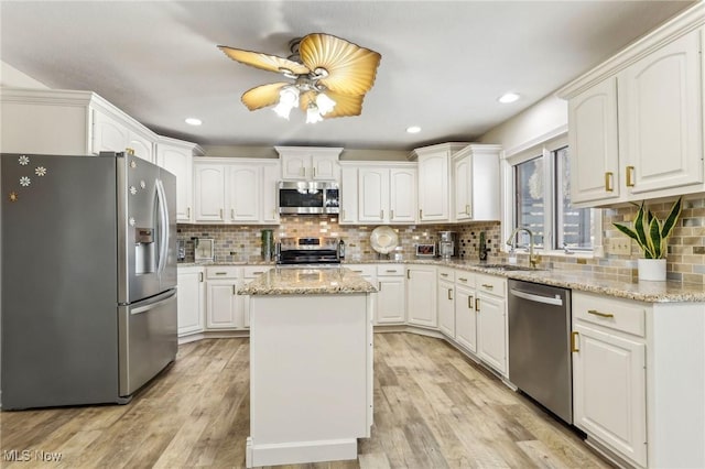 kitchen featuring stainless steel appliances, white cabinetry, a kitchen island, and sink