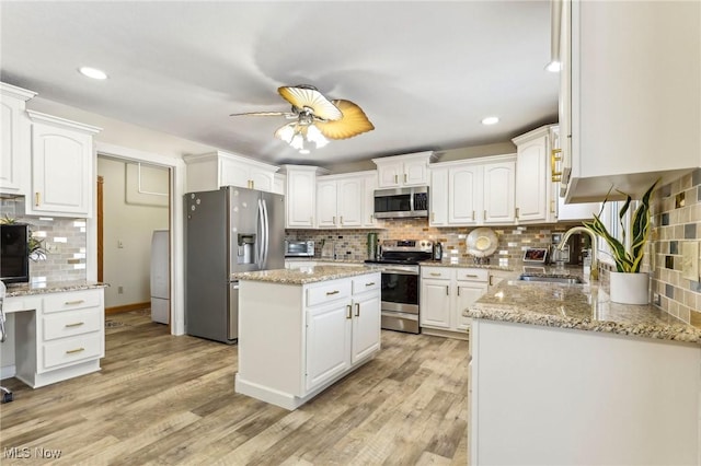 kitchen with sink, stainless steel appliances, white cabinets, and a kitchen island