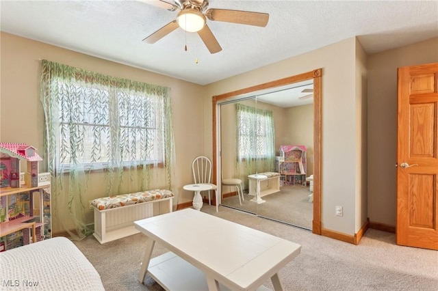 interior space with ceiling fan, carpet flooring, and a textured ceiling