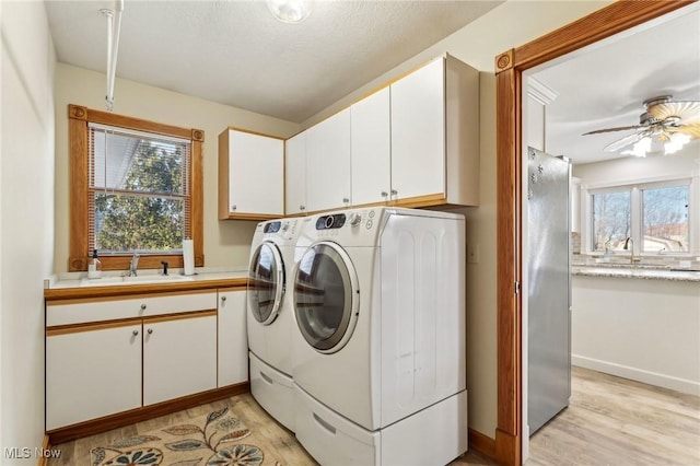 laundry area featuring sink, washer and clothes dryer, ceiling fan, cabinets, and light hardwood / wood-style floors