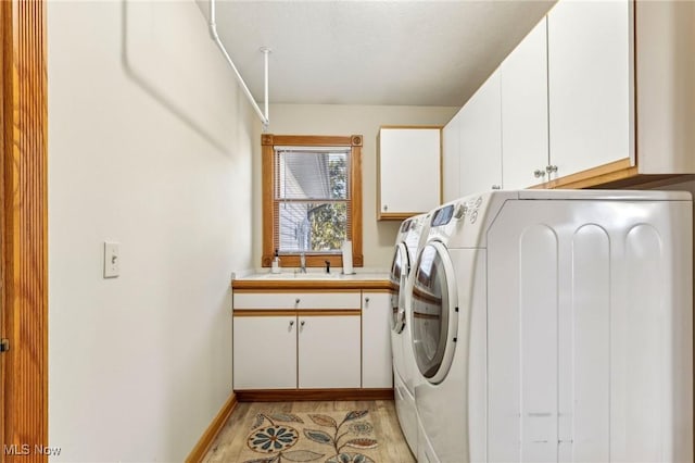 washroom featuring cabinets, sink, washer and clothes dryer, and light wood-type flooring