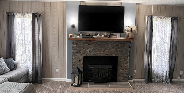 carpeted living room featuring wooden walls and a stone fireplace