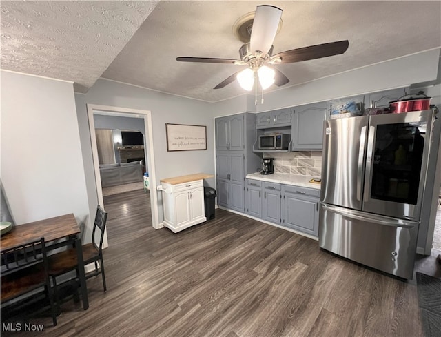 kitchen featuring gray cabinetry, tasteful backsplash, a textured ceiling, dark hardwood / wood-style floors, and stainless steel appliances