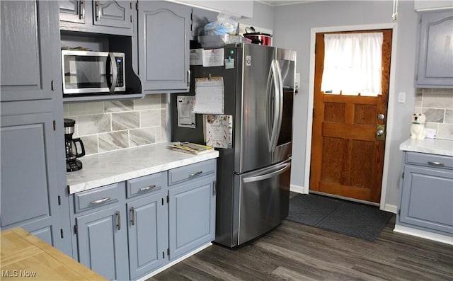 kitchen with decorative backsplash, dark wood-type flooring, and stainless steel appliances