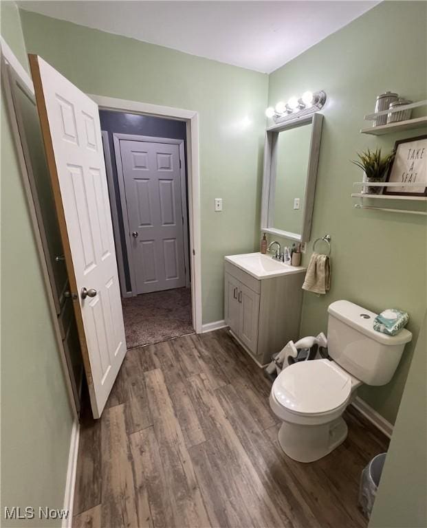 bathroom featuring wood-type flooring, toilet, and vanity