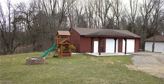 view of play area with a lawn, an outdoor structure, and an outdoor fire pit