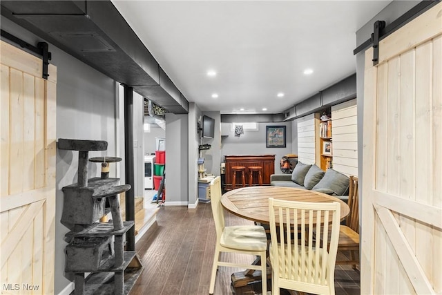 dining area with a barn door and dark wood-type flooring