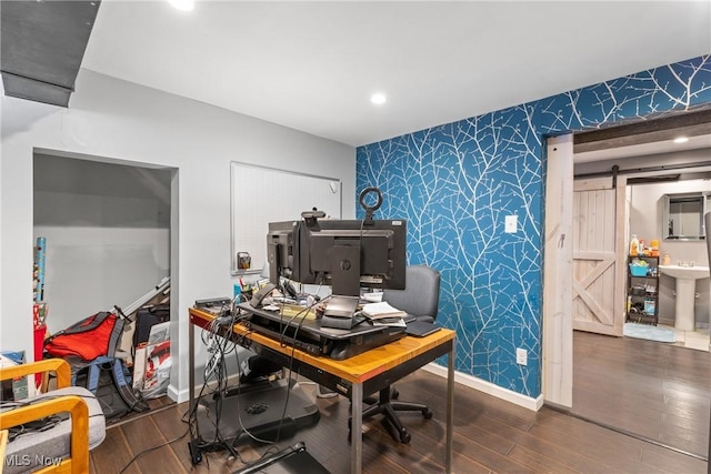 office with a barn door and hardwood / wood-style floors