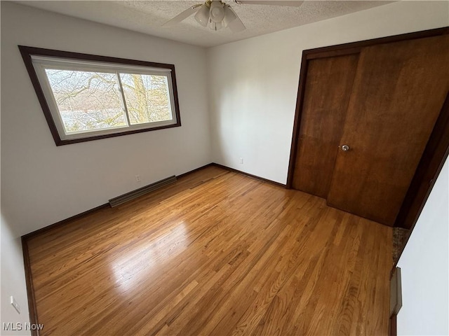 unfurnished bedroom featuring ceiling fan, a closet, light hardwood / wood-style flooring, and a textured ceiling