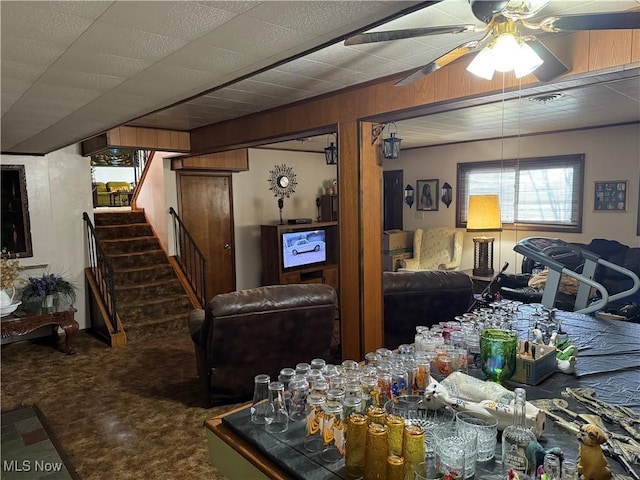 living room featuring ceiling fan, carpet floors, and wooden walls