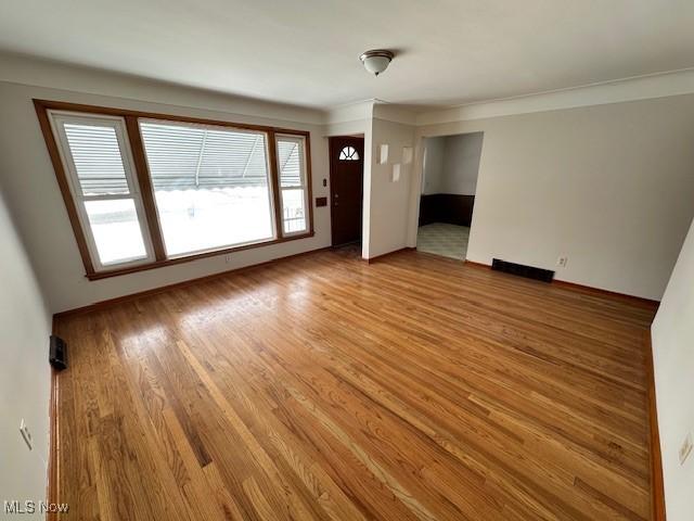 unfurnished living room featuring crown molding and wood-type flooring