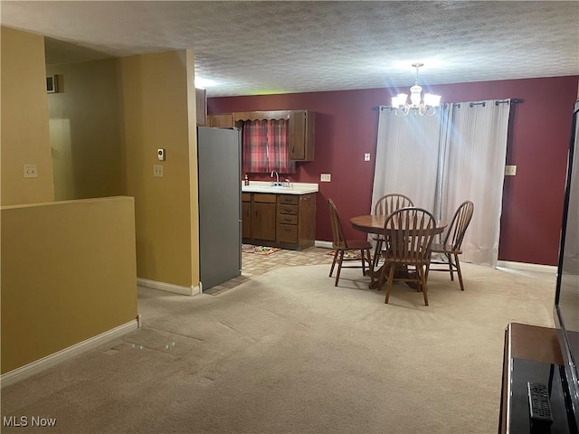 dining space featuring sink, a chandelier, light carpet, and a textured ceiling