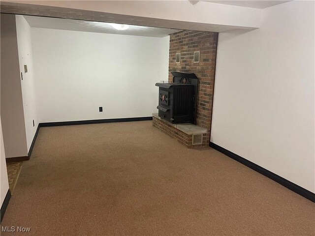 basement with carpet floors and a wood stove