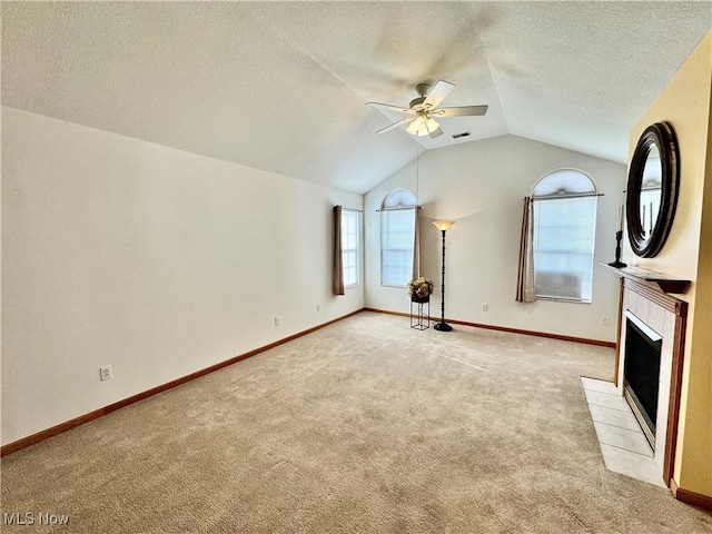 unfurnished living room with lofted ceiling, light carpet, a textured ceiling, ceiling fan, and a fireplace