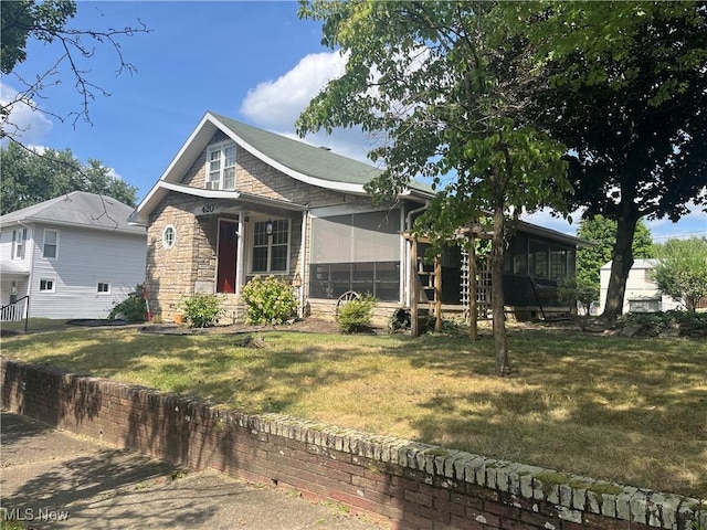 view of front of home featuring a sunroom and a front lawn