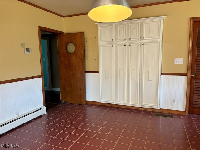 tiled empty room featuring ornamental molding and baseboard heating