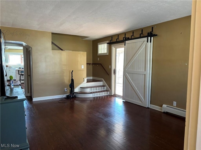 foyer featuring dark wood-type flooring, a baseboard radiator, a barn door, and a healthy amount of sunlight