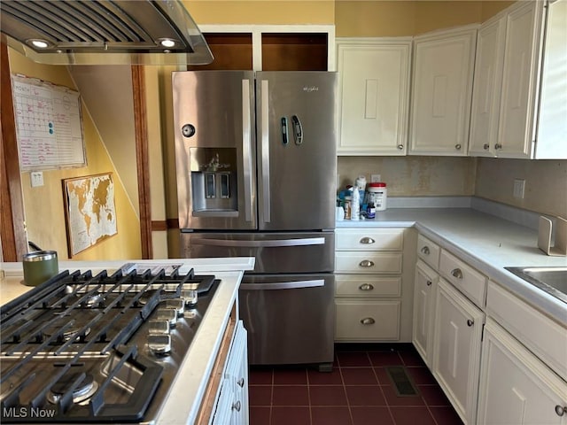 kitchen with stainless steel appliances, dark tile patterned floors, exhaust hood, and white cabinets