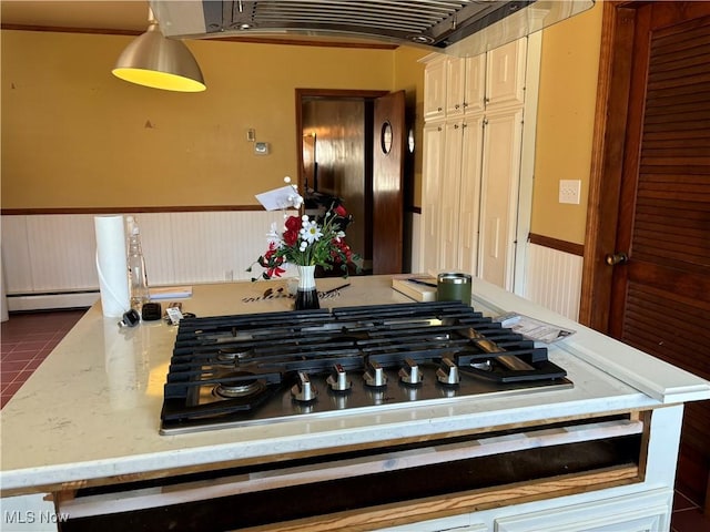 kitchen with light stone counters, hanging light fixtures, stainless steel gas stovetop, and a baseboard heating unit