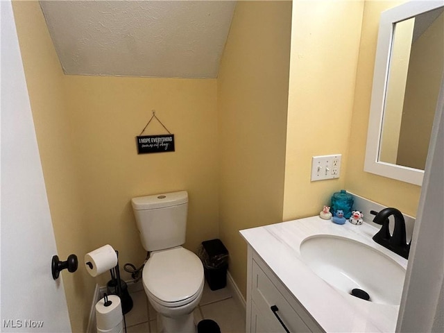 bathroom with vanity, a textured ceiling, vaulted ceiling, tile patterned floors, and toilet