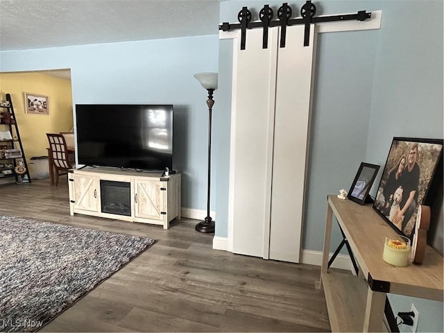 living room with wood-type flooring, a barn door, and a textured ceiling