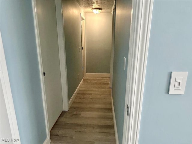 hall with light hardwood / wood-style flooring and a textured ceiling