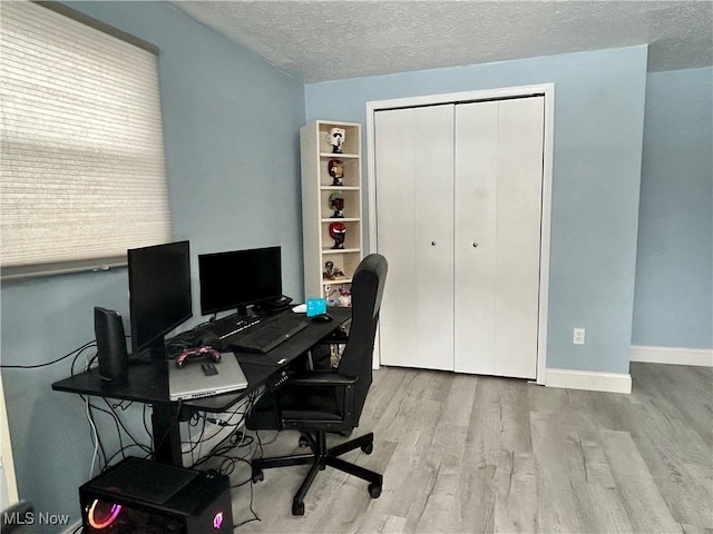 home office featuring light hardwood / wood-style flooring and a textured ceiling