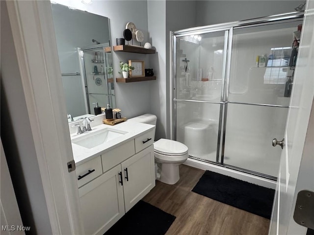 bathroom featuring hardwood / wood-style flooring, vanity, toilet, and a shower with shower door