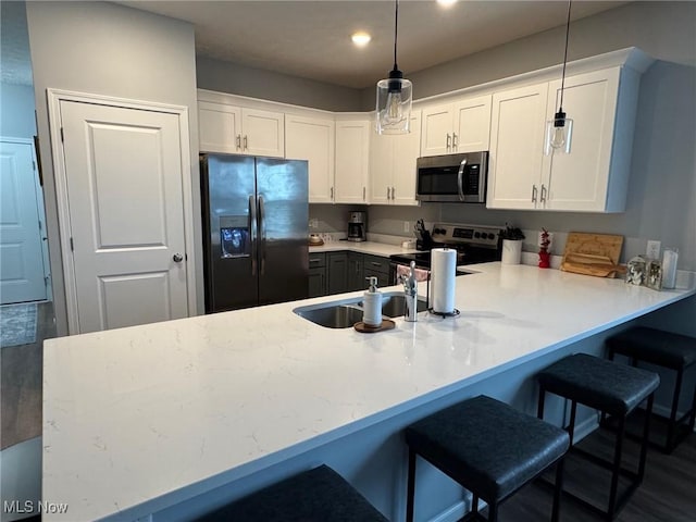 kitchen featuring appliances with stainless steel finishes, pendant lighting, white cabinetry, a kitchen breakfast bar, and kitchen peninsula