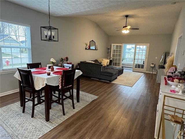 dining room featuring dark hardwood / wood-style flooring, a textured ceiling, vaulted ceiling, and a healthy amount of sunlight