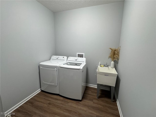 washroom featuring dark wood-type flooring, washing machine and clothes dryer, and a textured ceiling