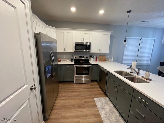 kitchen with pendant lighting, sink, white cabinetry, stainless steel appliances, and kitchen peninsula