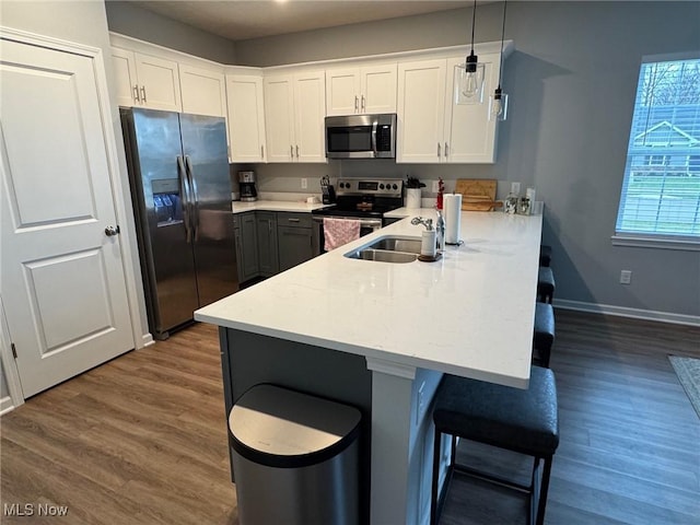 kitchen with white cabinetry, appliances with stainless steel finishes, kitchen peninsula, and decorative light fixtures