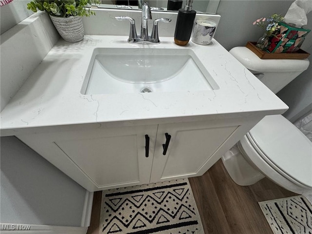 bathroom featuring wood-type flooring, vanity, and toilet