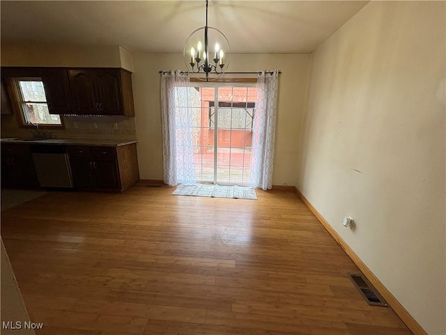 unfurnished dining area featuring a wealth of natural light, visible vents, light wood-style floors, and a chandelier