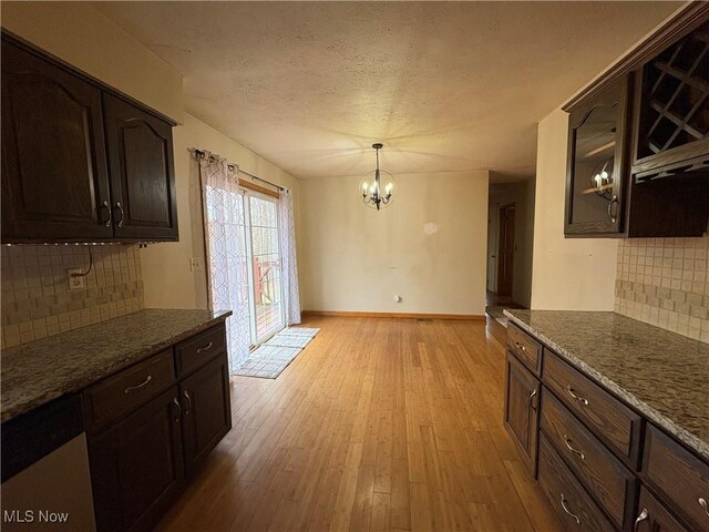 kitchen with a textured ceiling, a notable chandelier, dark brown cabinetry, and light wood finished floors