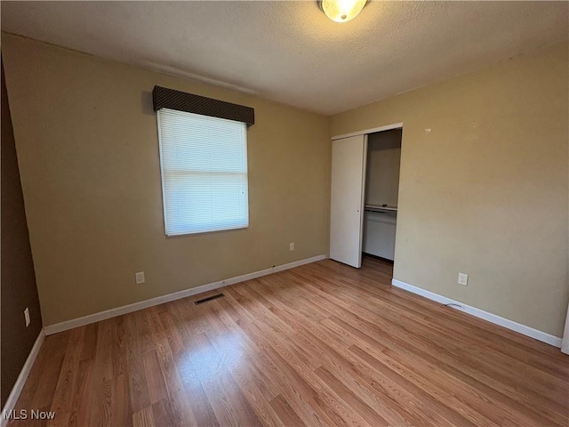 unfurnished bedroom with light wood-style flooring, baseboards, and a closet