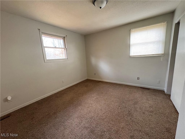 carpeted spare room with baseboards and a textured ceiling